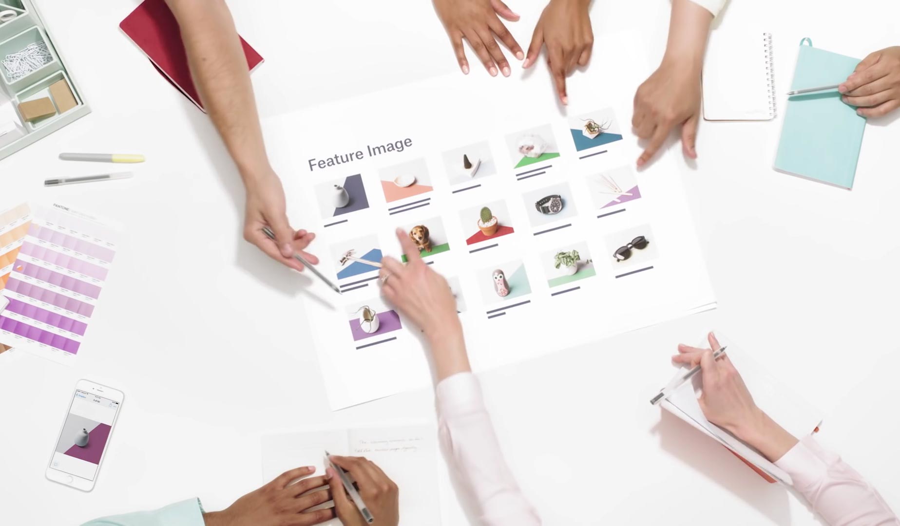 Multiple hands pointing to a piece of paper with images under review