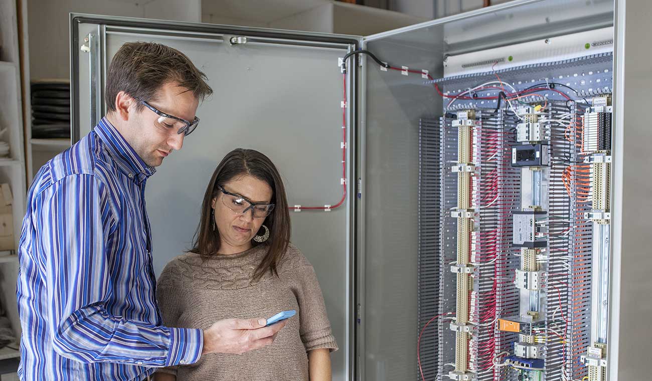 Photo of two CEL Electric employees looking at a smartphone