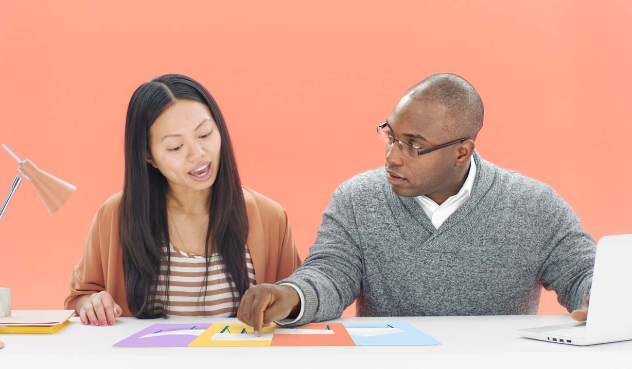 Photo of two co-workers looking over a project at a desk