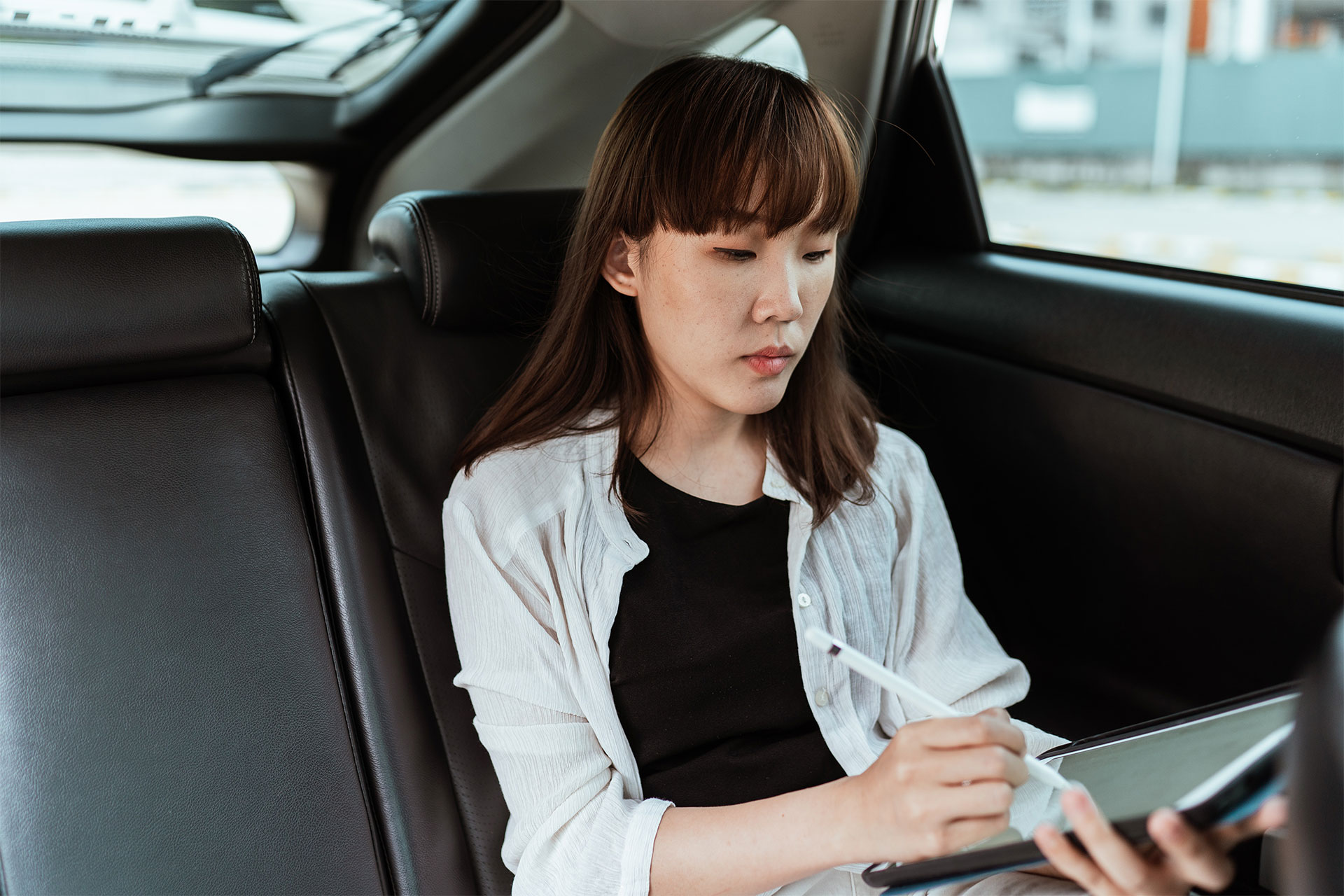 Een vrouw die iets op een tablet ondertekent terwijl ze in een auto zit