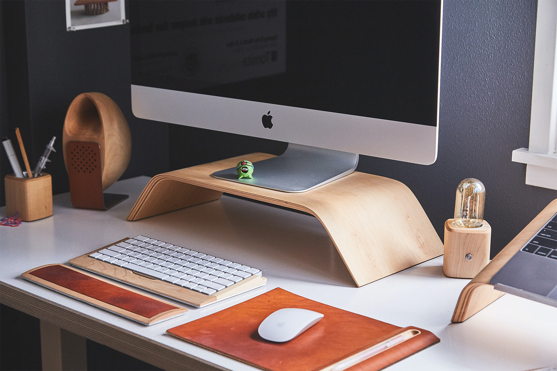무선 키보드, 마우스와 함께 책상 위 목재 스탠드에 놓여 있는 iMac