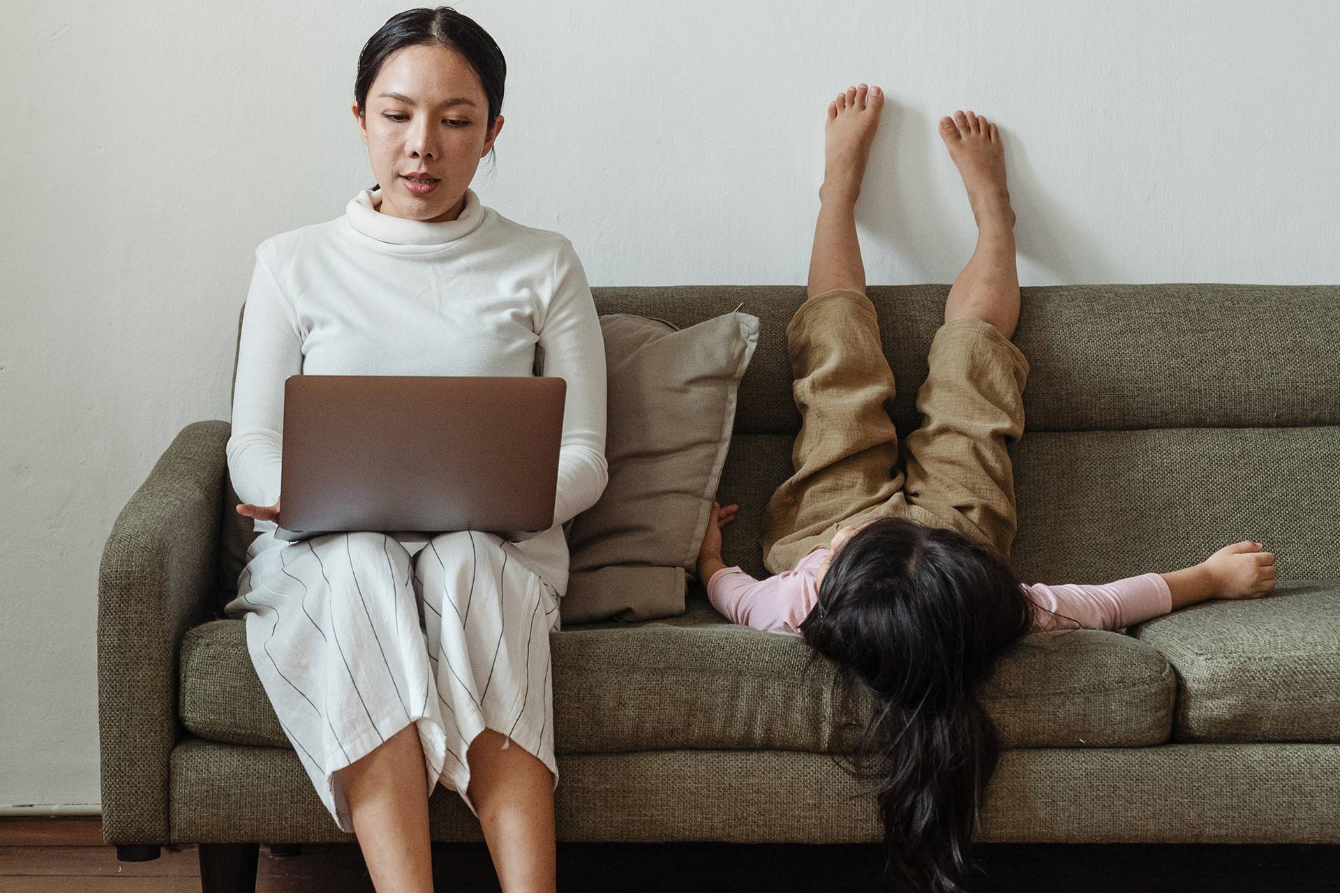 Een persoon die vanuit huis op een laptop werkt met een kind