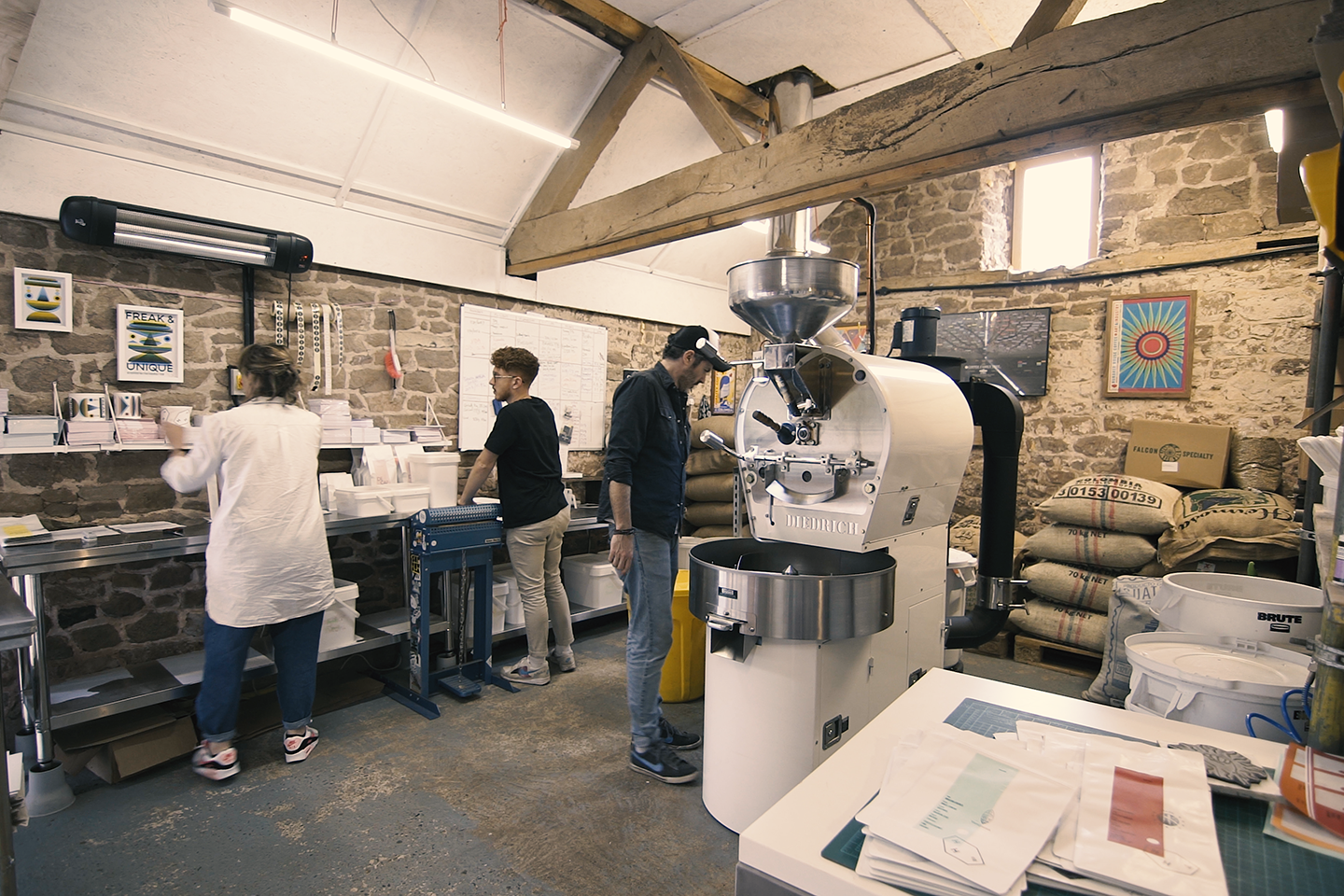 Two men and a woman work in the back room of a roastery.