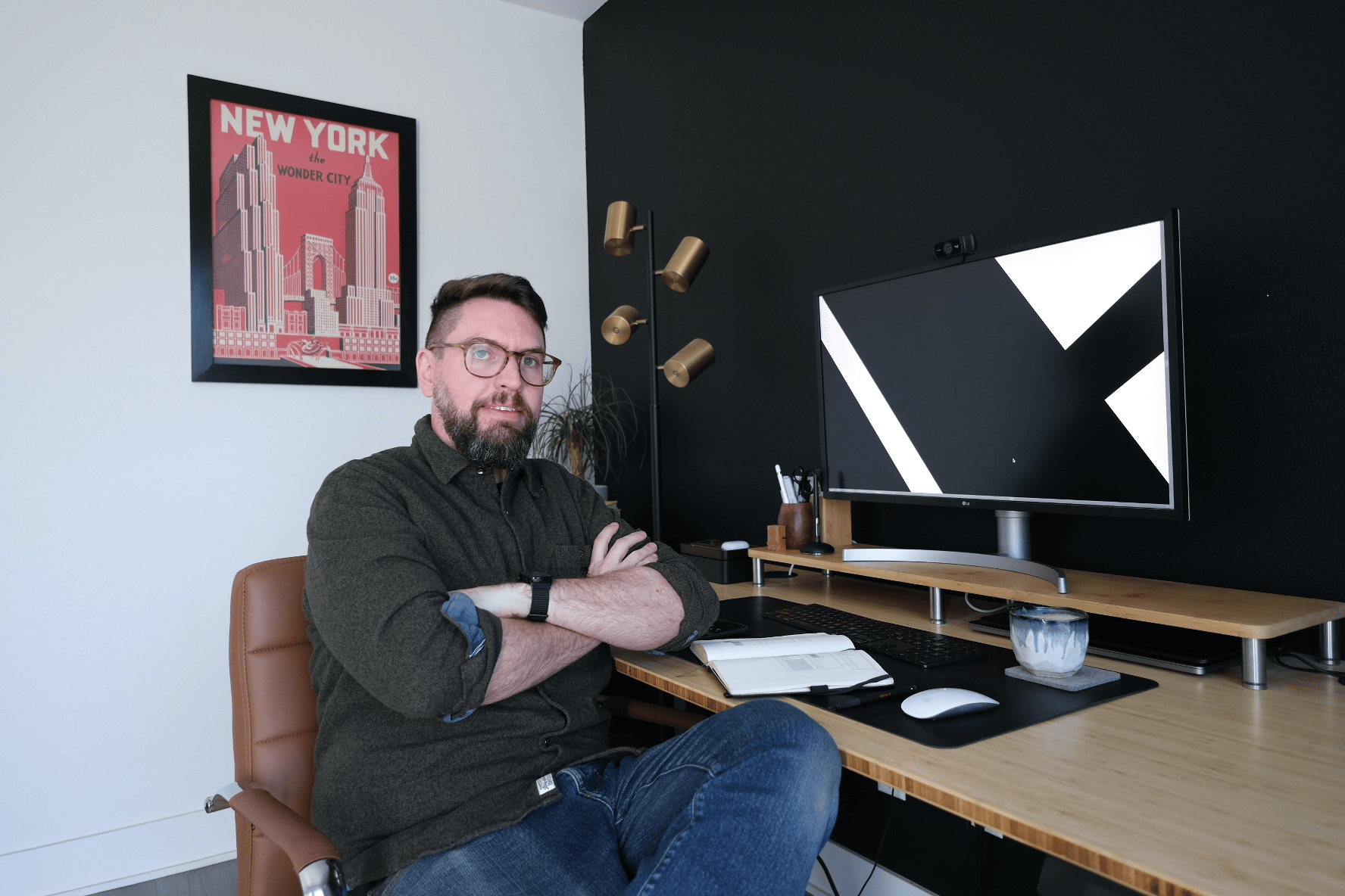 Creatief directeur David Tucker zit met zijn armen over elkaar voor een desktopcomputer in zijn kantoor.