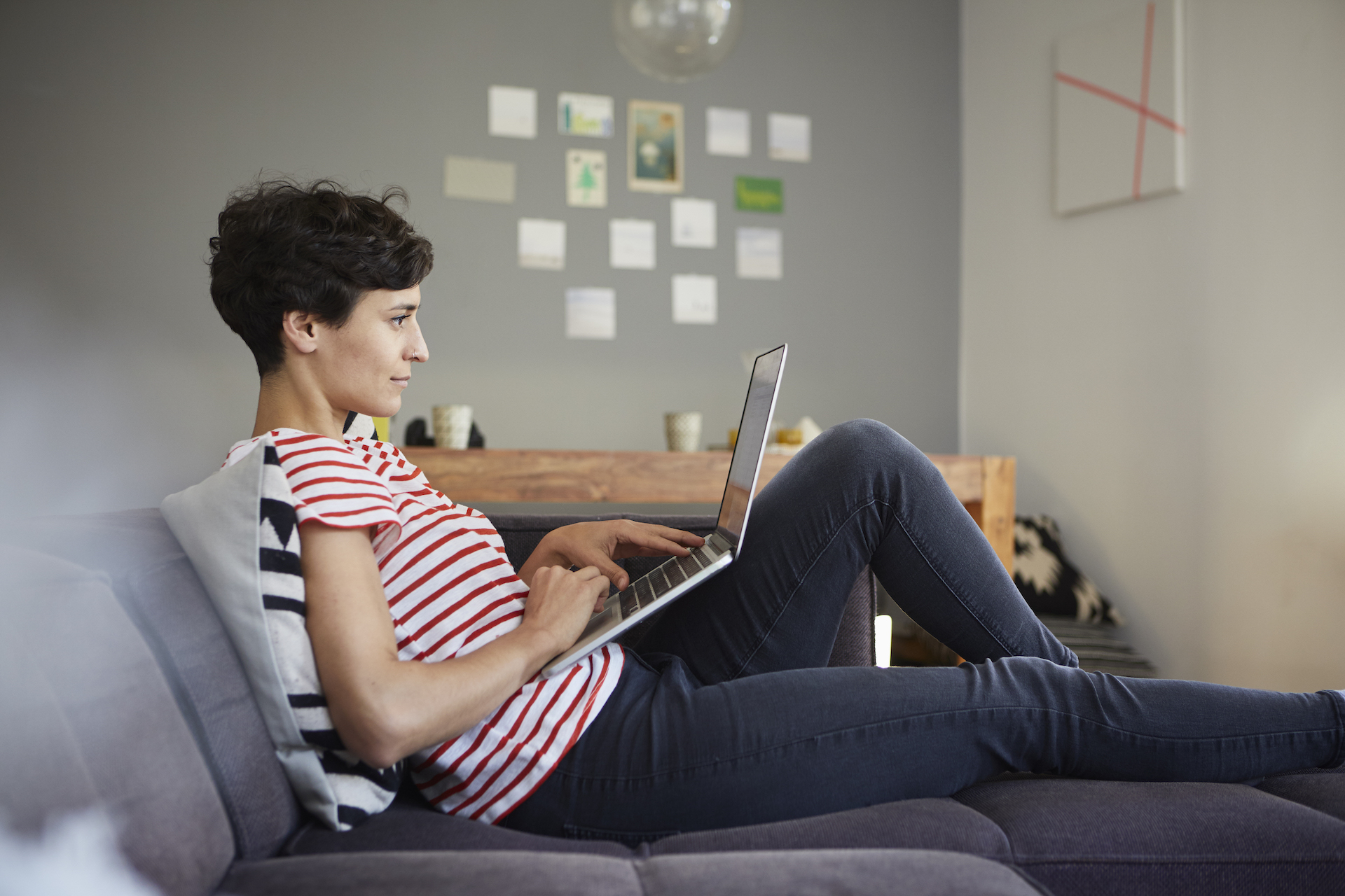Mujer trabajando desde casa con un portátil y reclinada