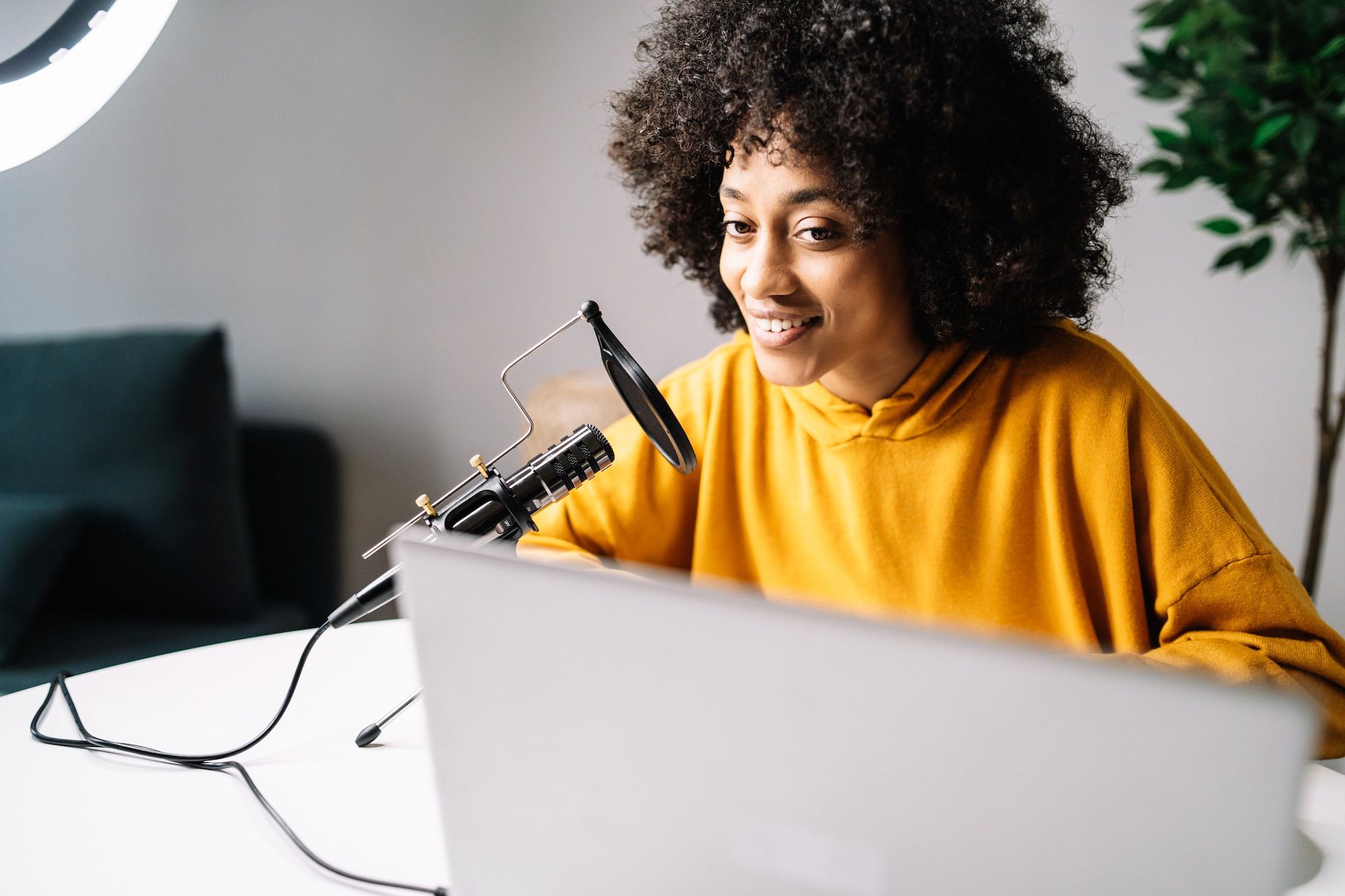 una mujer realiza una grabación con un micrófono en una computadora portátil que está sobre su escritorio