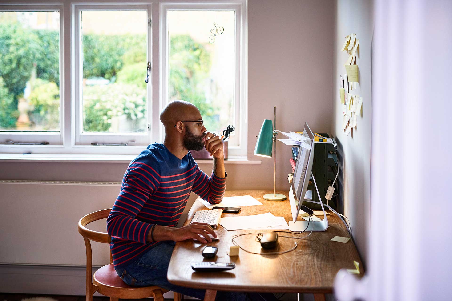 机に向かってマウスを持ち、パソコンの画面を見ている男性