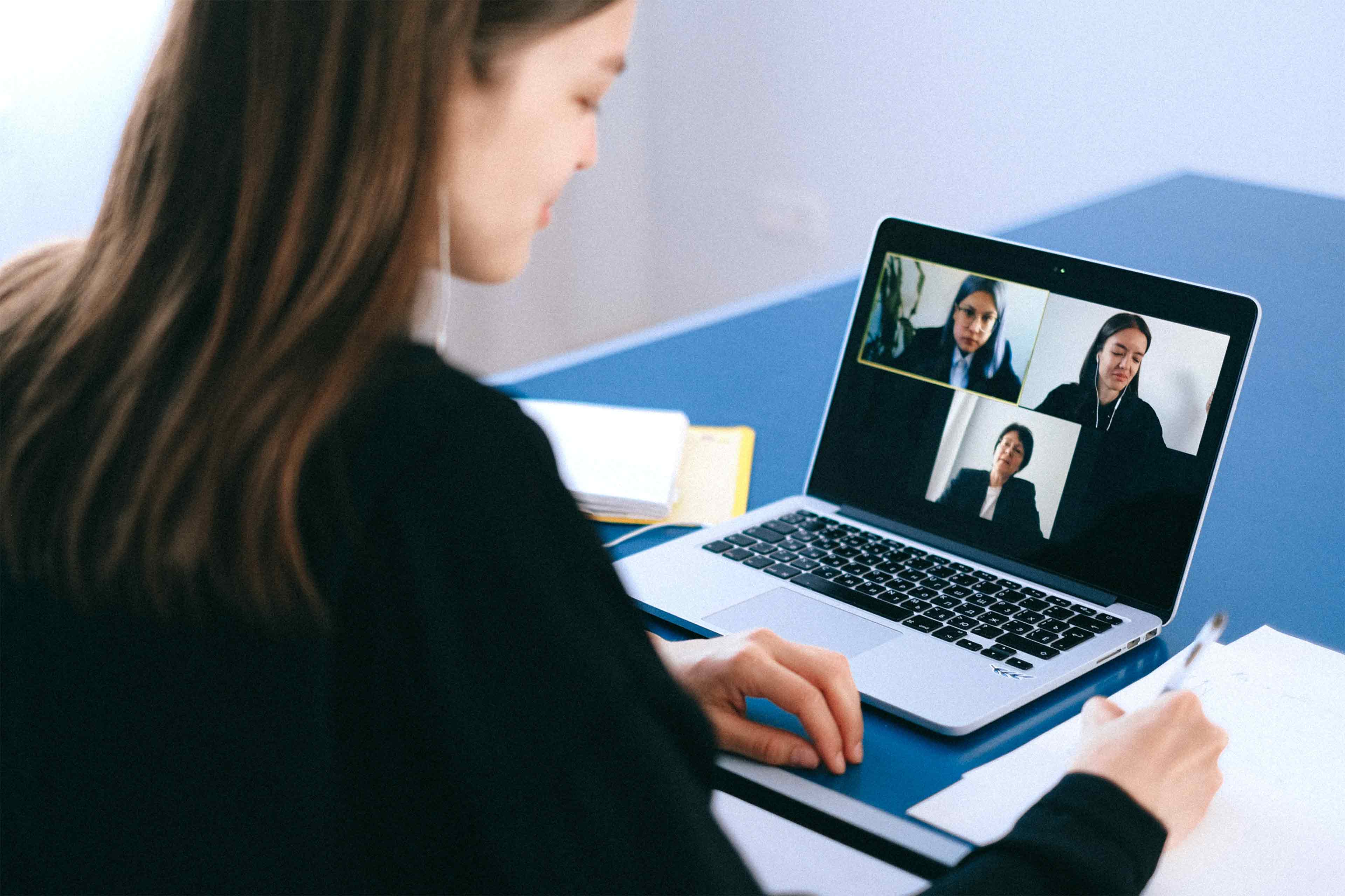 Eine Person macht einen Videoanruf auf einem Laptop mit zwei anderen Teilnehmern