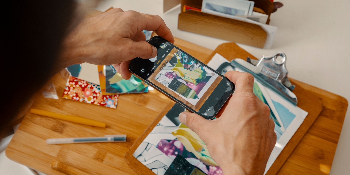 A person takes a photo of a collage on their desk with a mobile phone