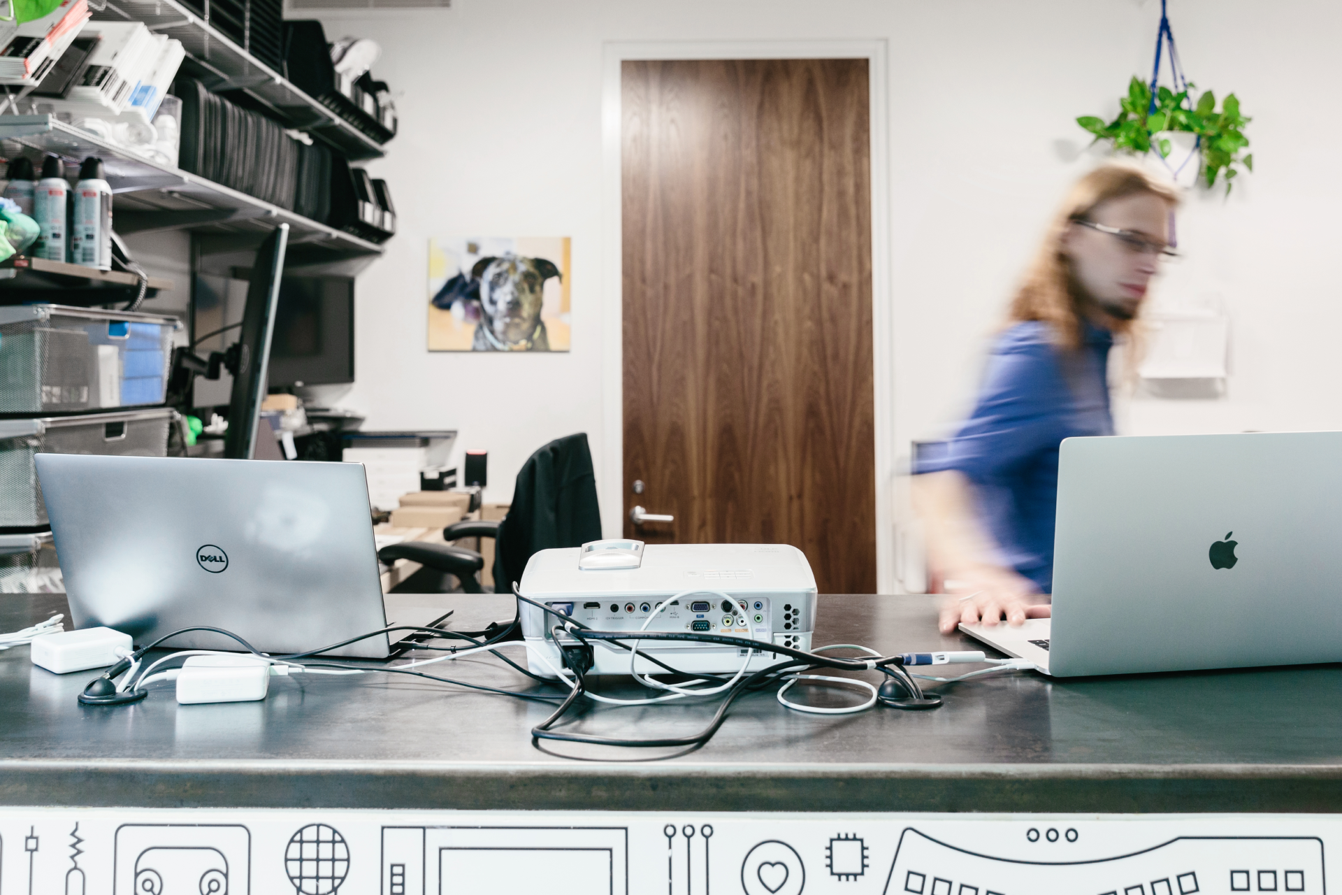 An image of a person working across two laptops with a data storage device in-between.