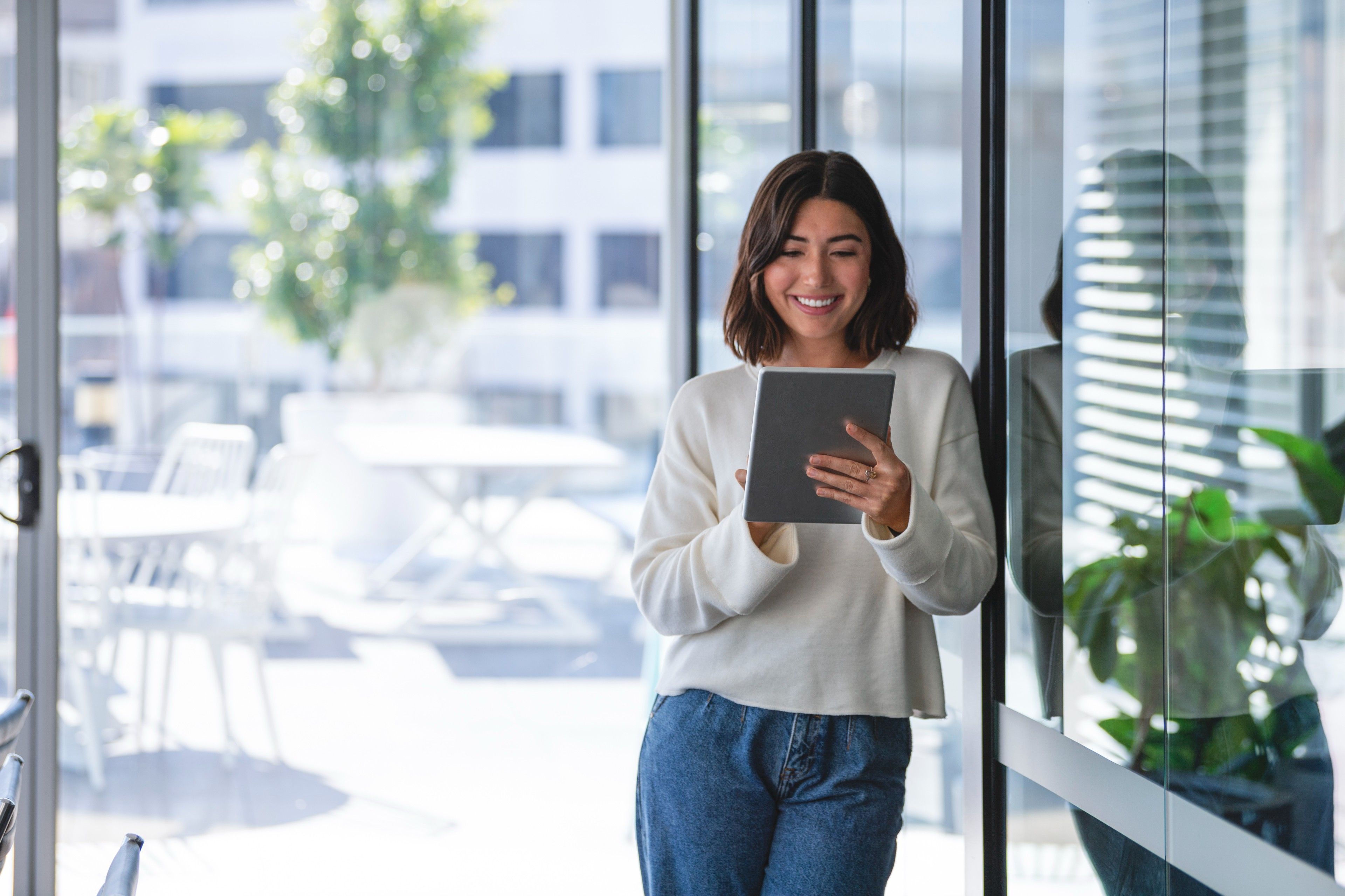 Woman stands outside a building while looking at her tablet