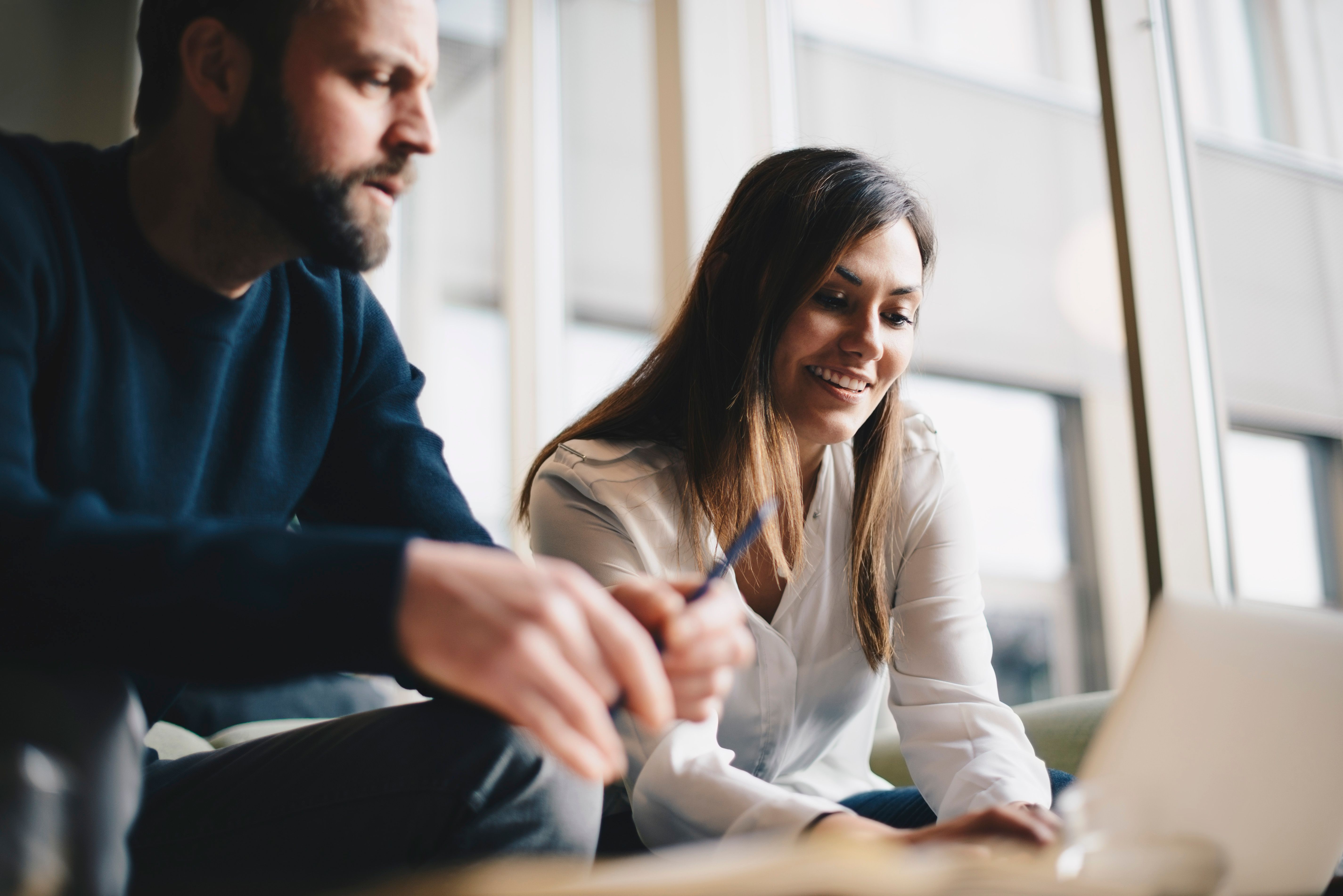 Two people look at a laptop in an office setting