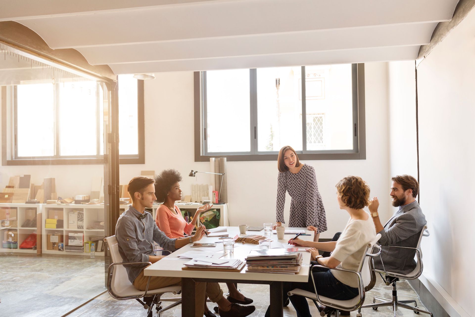 Cinco miembros de un equipo colaborando en una mesa de oficina.