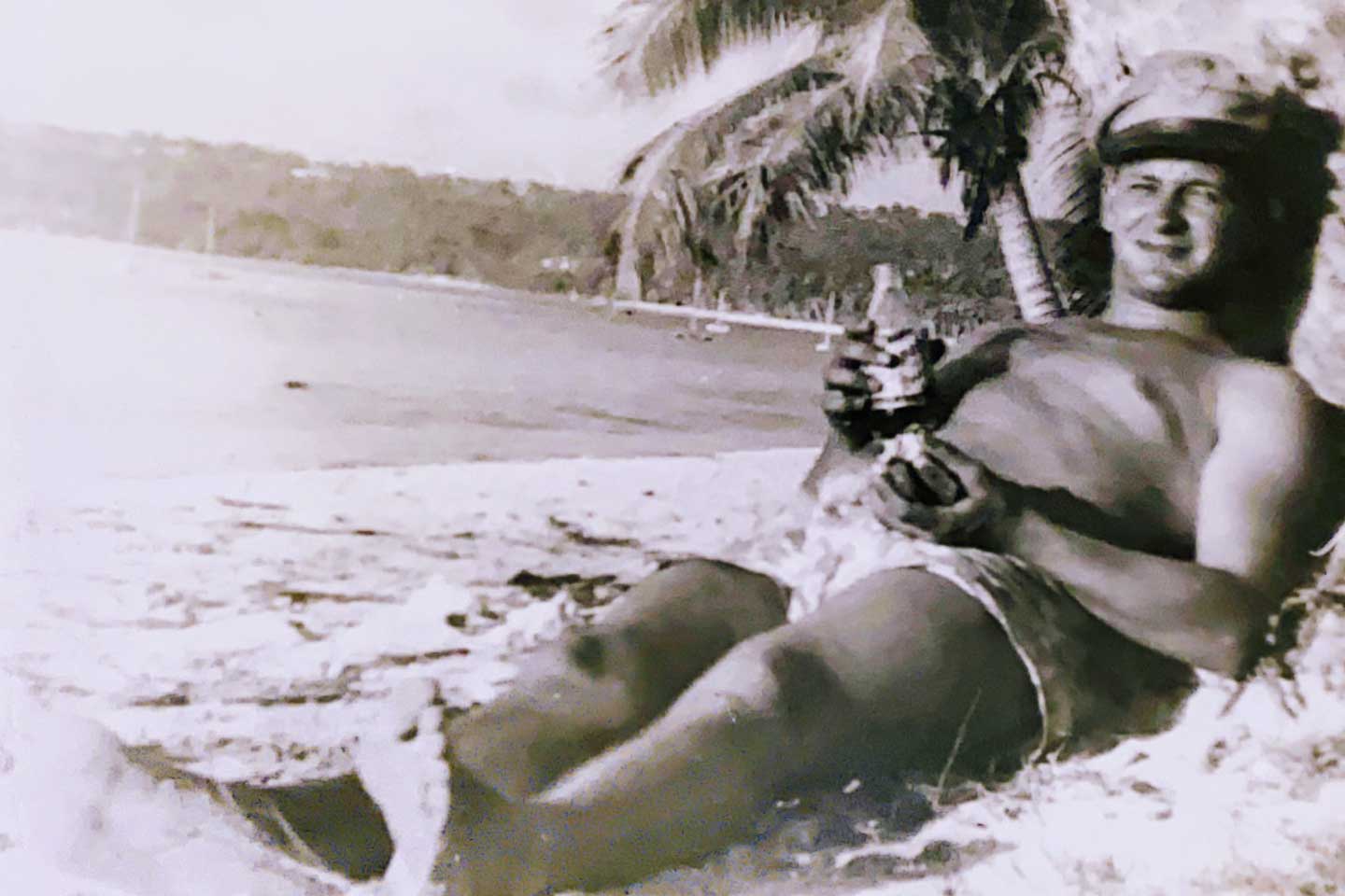 Young Paul laying shirtless on the beach
