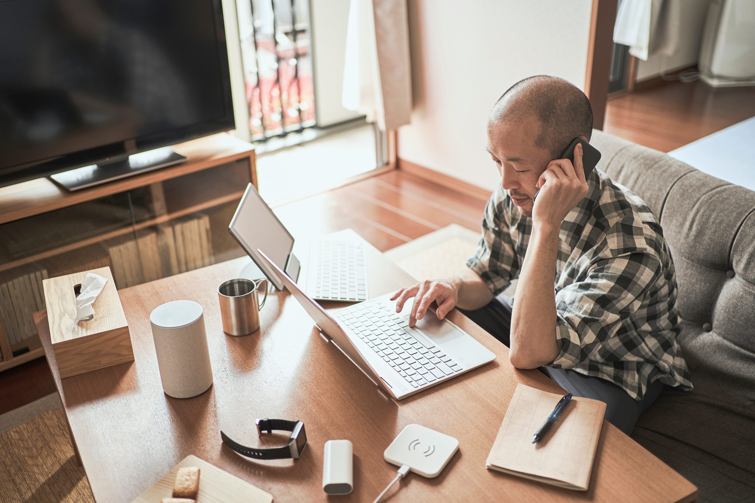 Una persona en una conversación telefónica sobre el teletrabajo mientras trabaja con un portátil