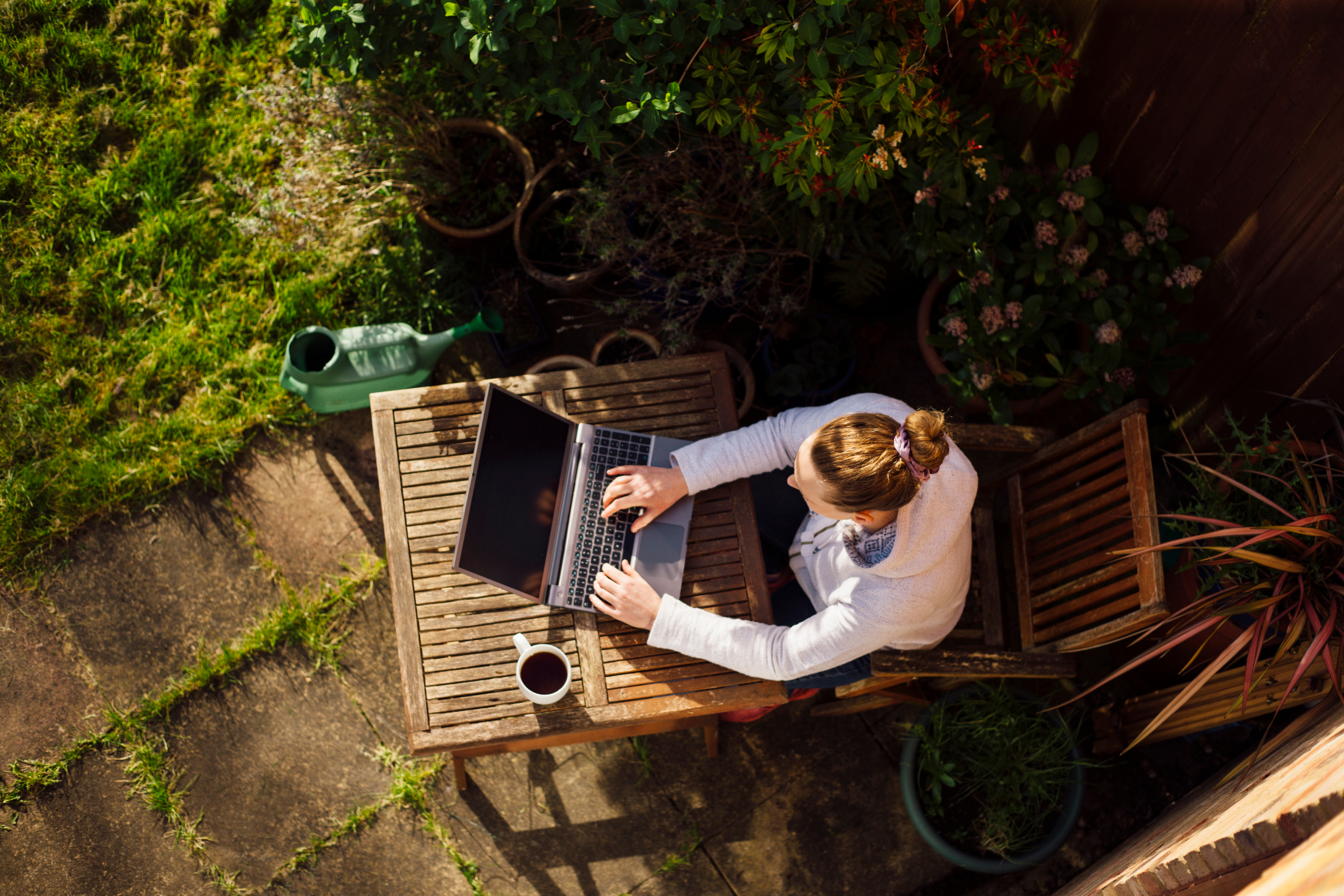 A person remotely working outdoors on a laptop