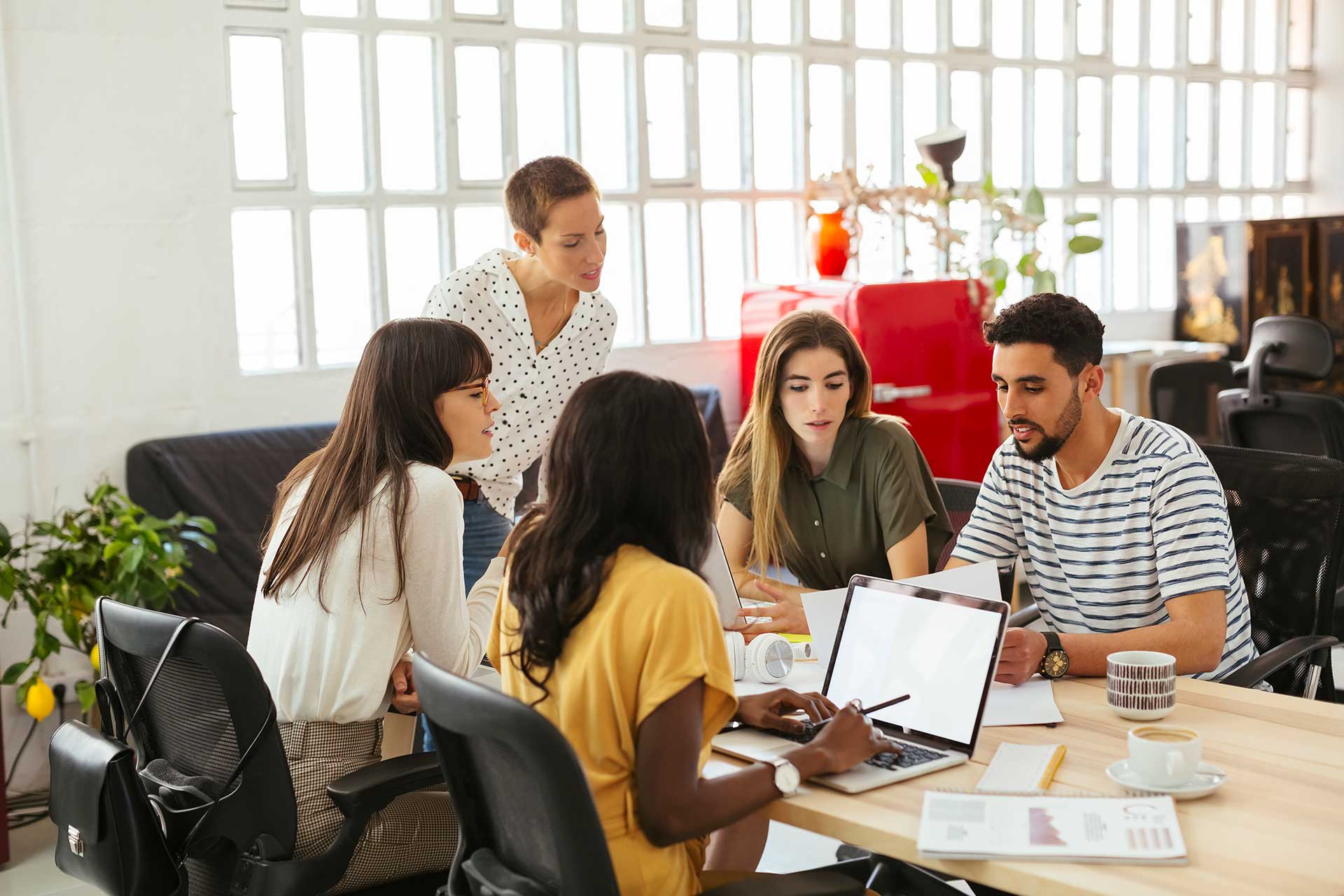 Group of 5 people sitting around table, reviewing papers