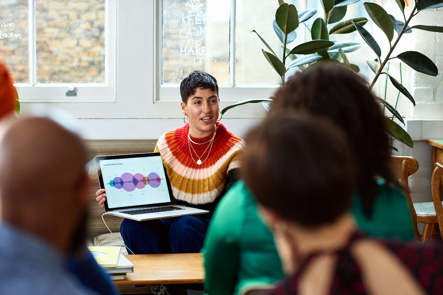 Hispanic person sharing computer graphics with team of creative business people.