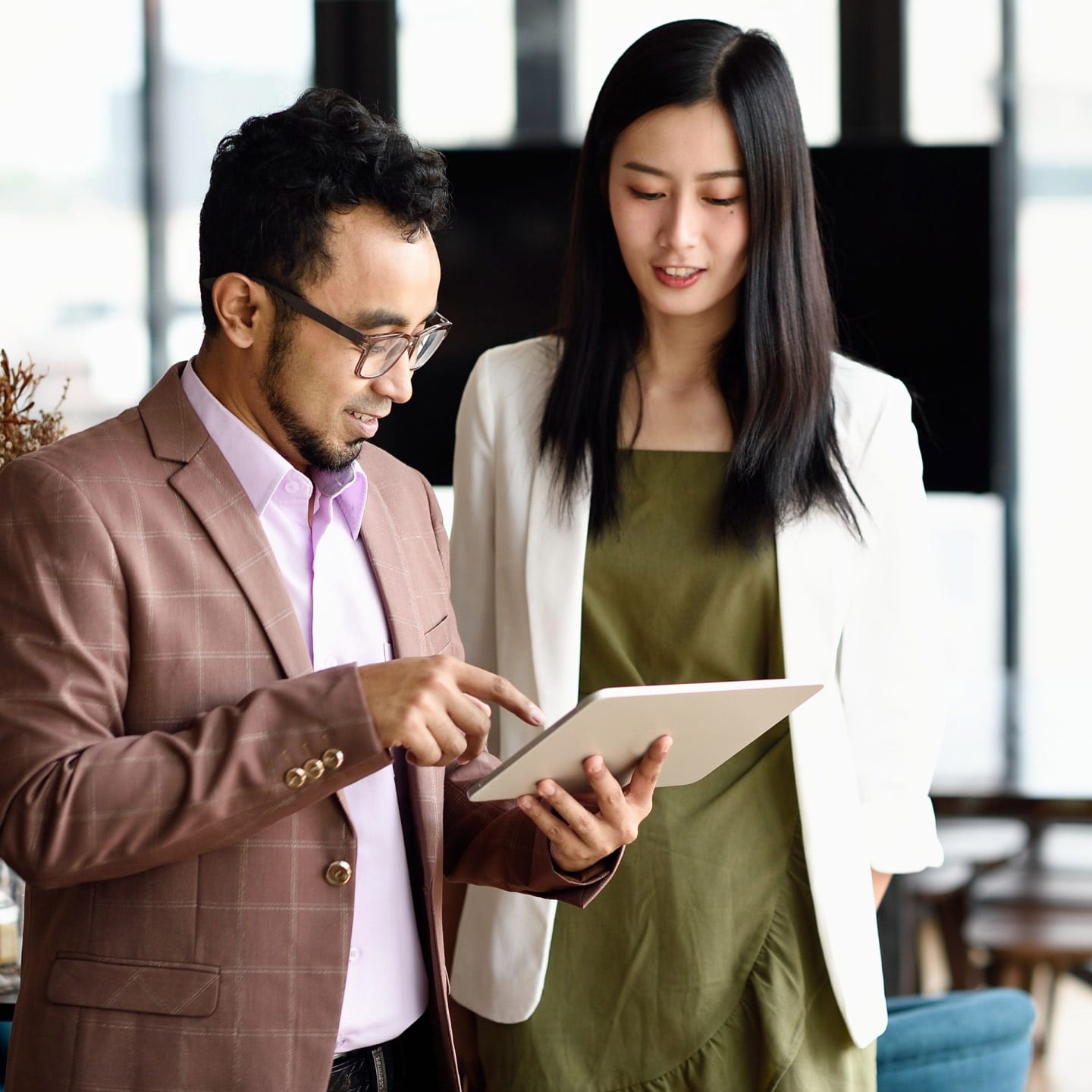 two people standing, looking at a digital tablet