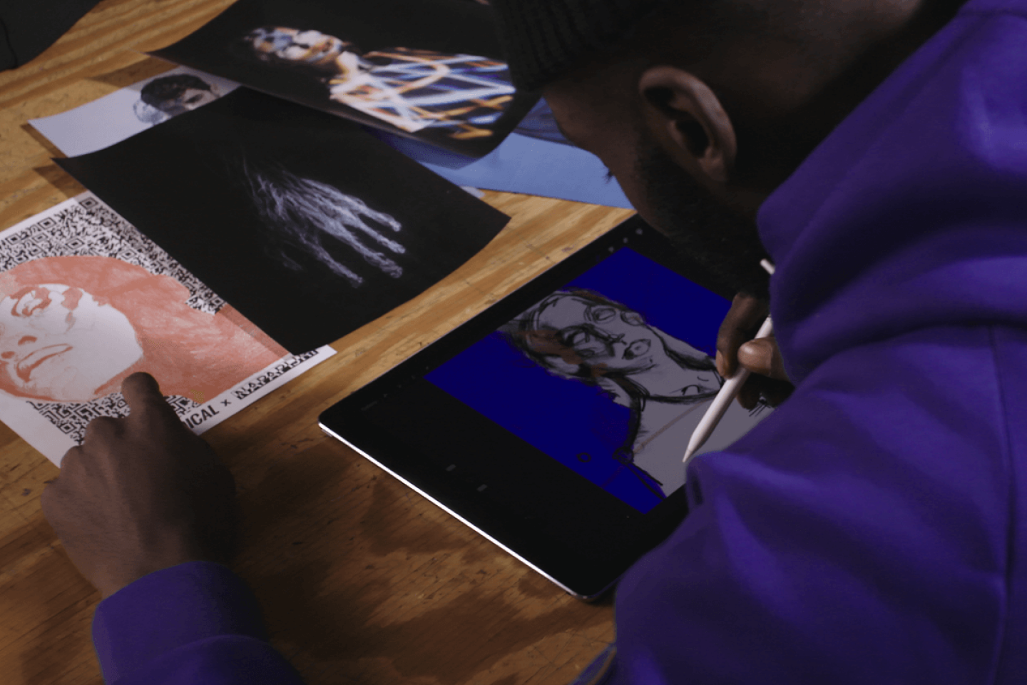 person illustrates on tablet from reference photos