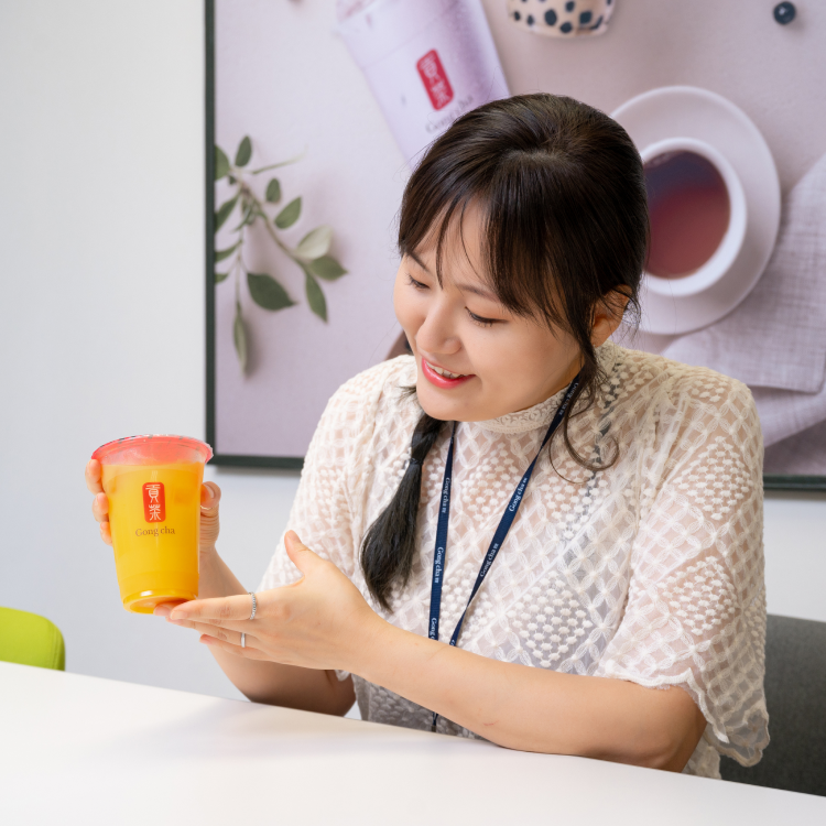 seorang wanita memegang minuman teh ais berwarna oren