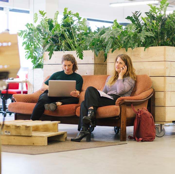 two women working together on an orange couch