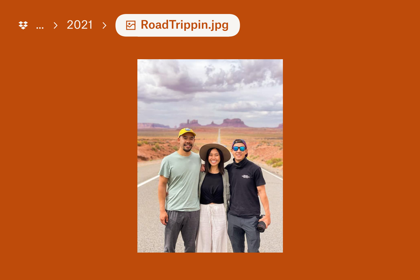 Three people standing in the road surrounded by the Arizona desert landscape