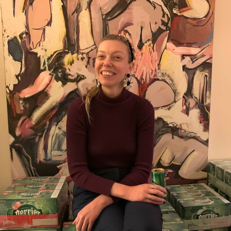 A woman sitting on top of boxes of different flavored Perrier water