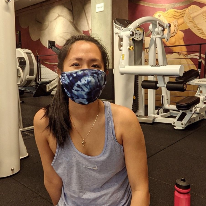 A woman wearing a mask and workout clothes in a gym