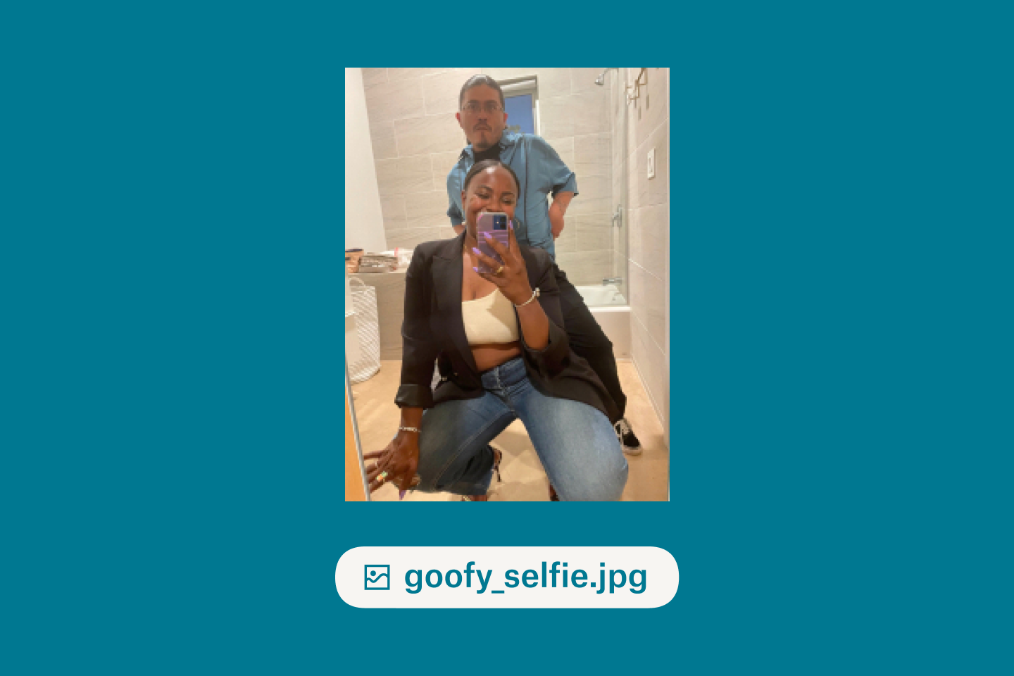 A man and a woman taking a goofy selfie in a bathroom mirror
