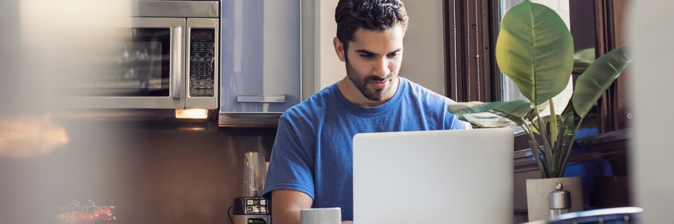 Personne assise devant son ordinateur dans sa cuisine