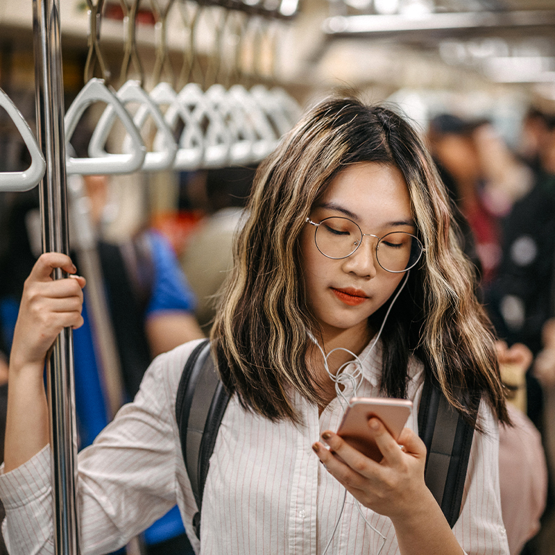 A woman looks at her cell phone while standing in a subway car