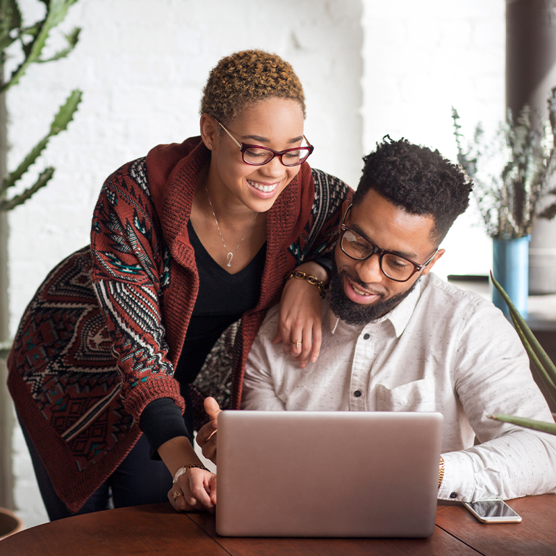 Two people look at a computer together and smile