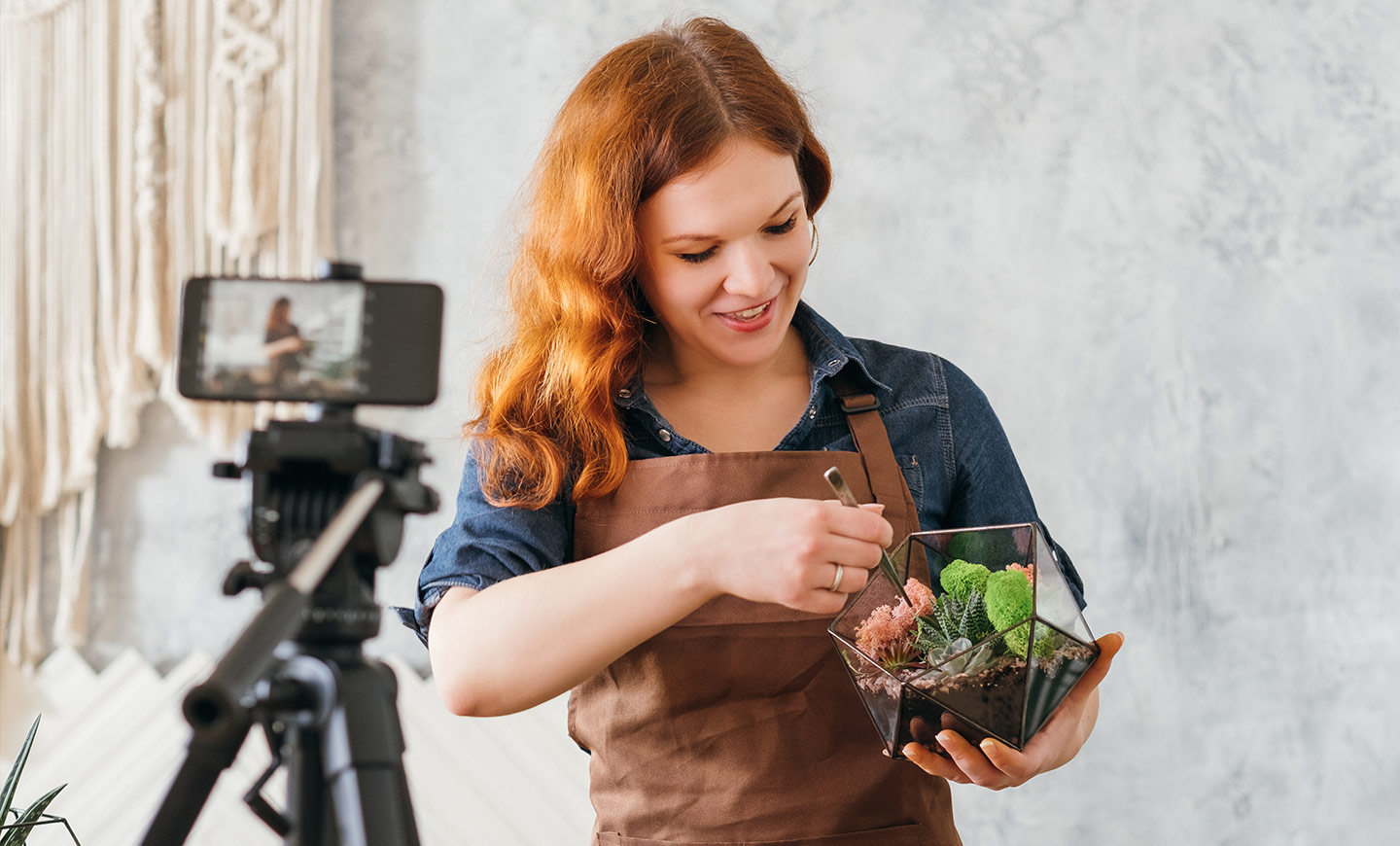一名花店店員一邊栽種多肉植物，一邊使用智慧型手機直播居家園藝線上教學