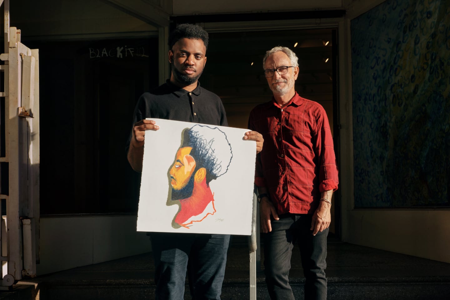 Joseph 'JD' Green and Glenn Peckman of Creativity Explored hold up a piece of art.