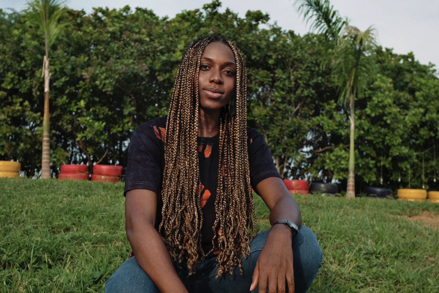 Benita Nnachortam, seorang fotografer Nigeria, pengusaha, dan aktivis, sedang duduk di sebuah lapangan.