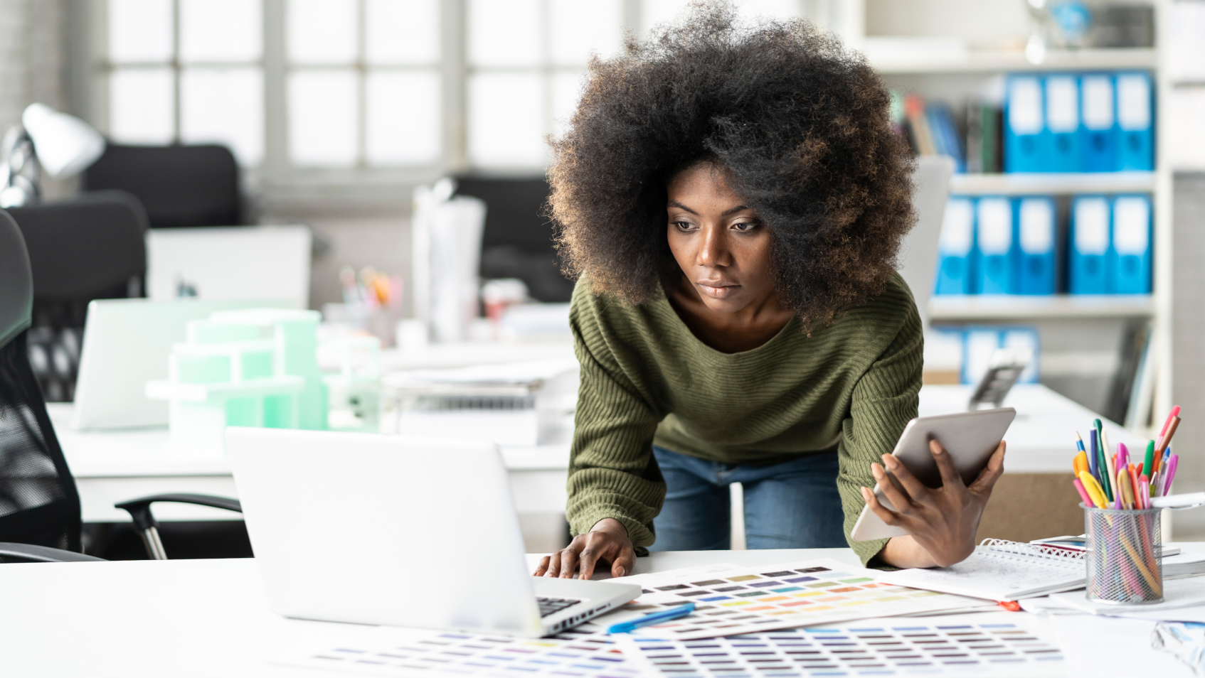 Professionnelle de la création travaillant sur un ordinateur portable et une tablette connectés au même réseau