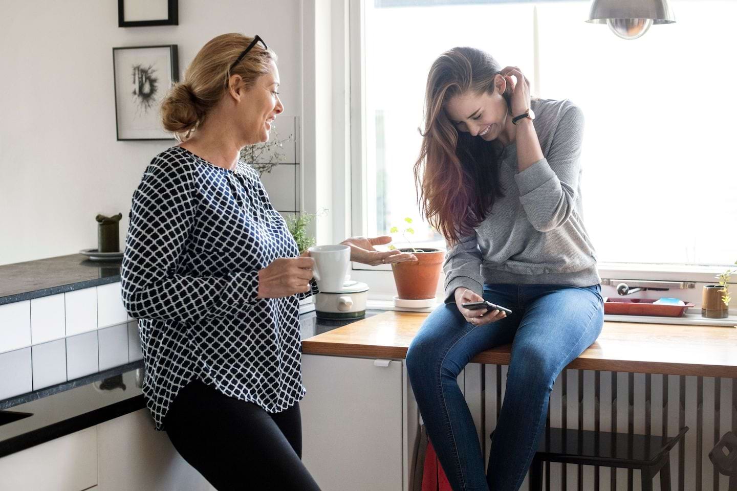 Dos mujeres se ríen mientras una de ellas toma café