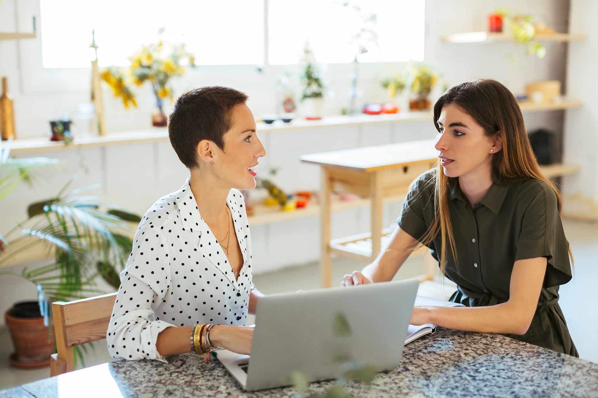 A photograph of two people sat in front of a laptop, with one of the pair looking concerned