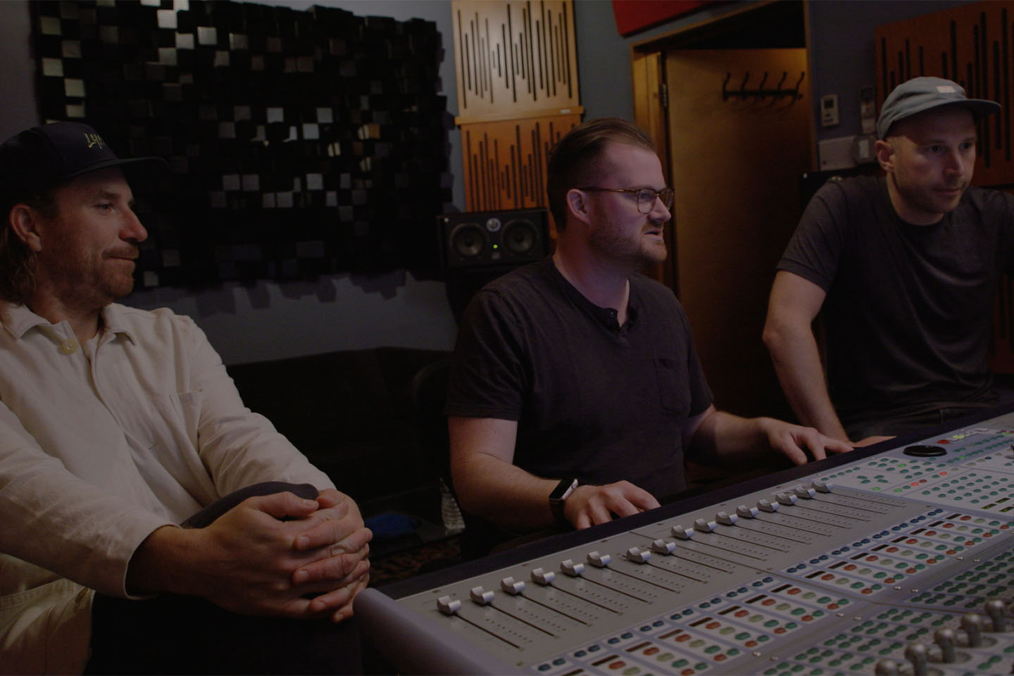 Tres músicos trabajan en una consola de sonido