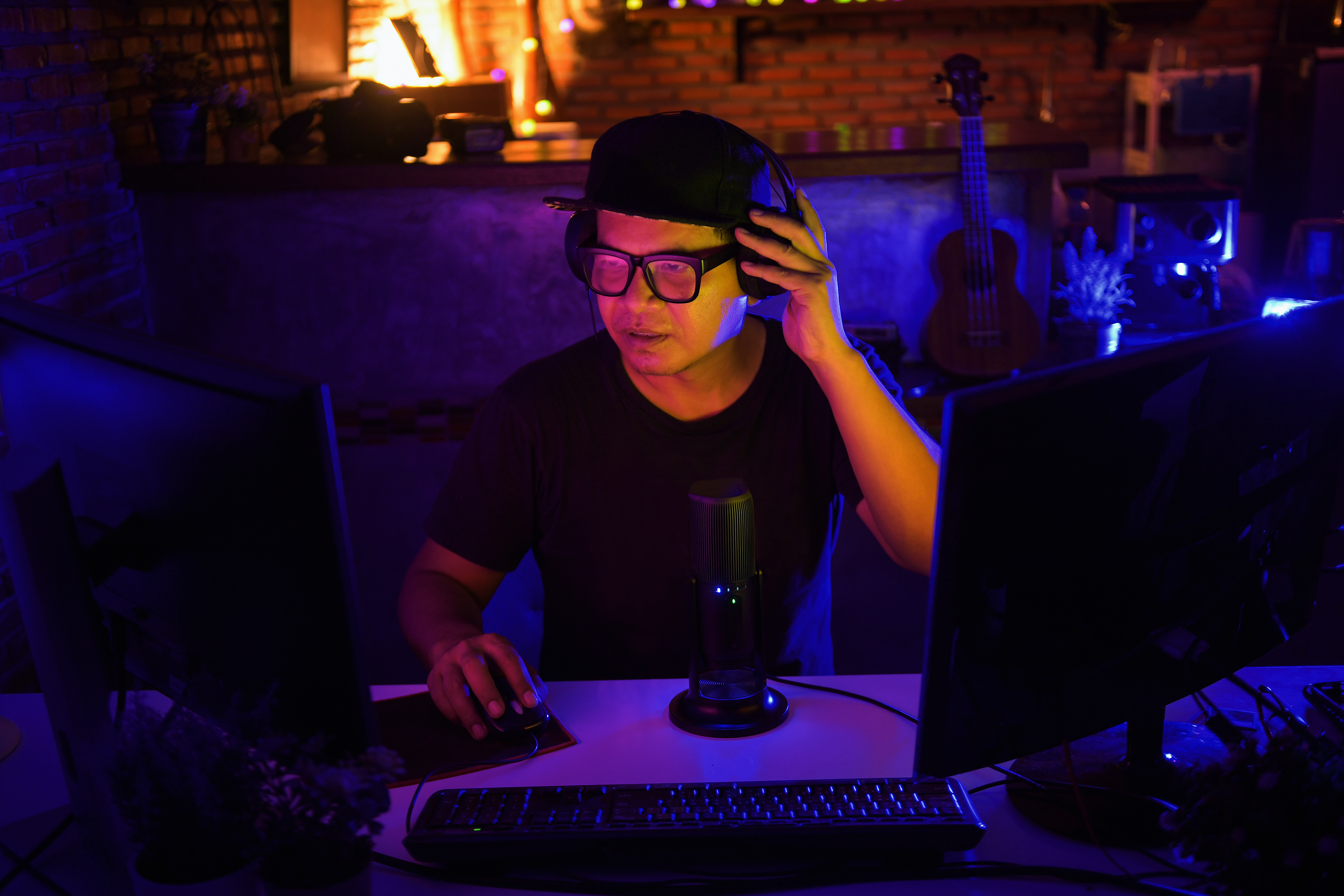 A video editor records a voiceover for a project while sitting in front of two monitors.