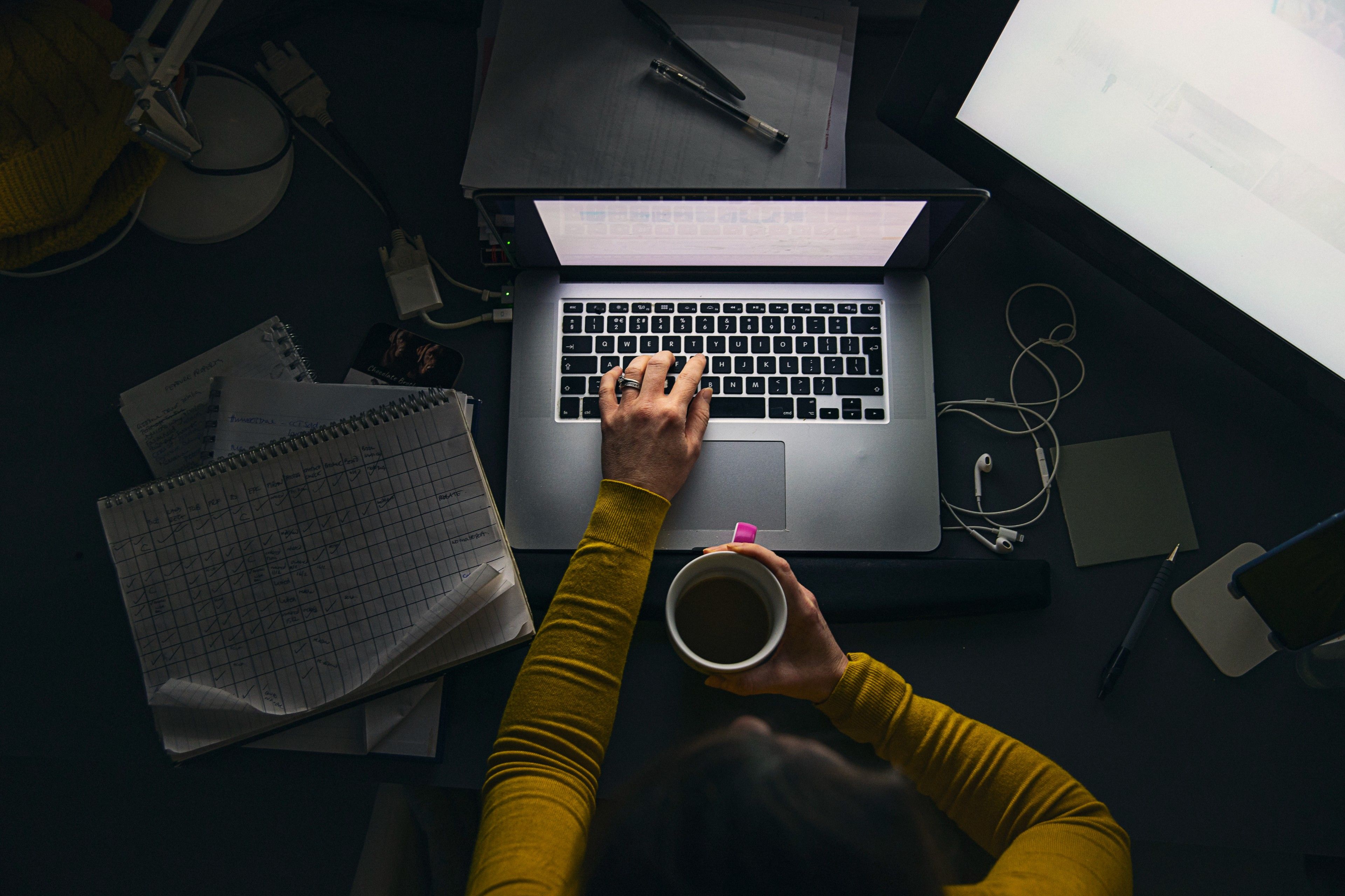 Entrepreneuse travaillant la nuit sur son ordinateur portable, avec une tasse de café et un tableur à ses côtés