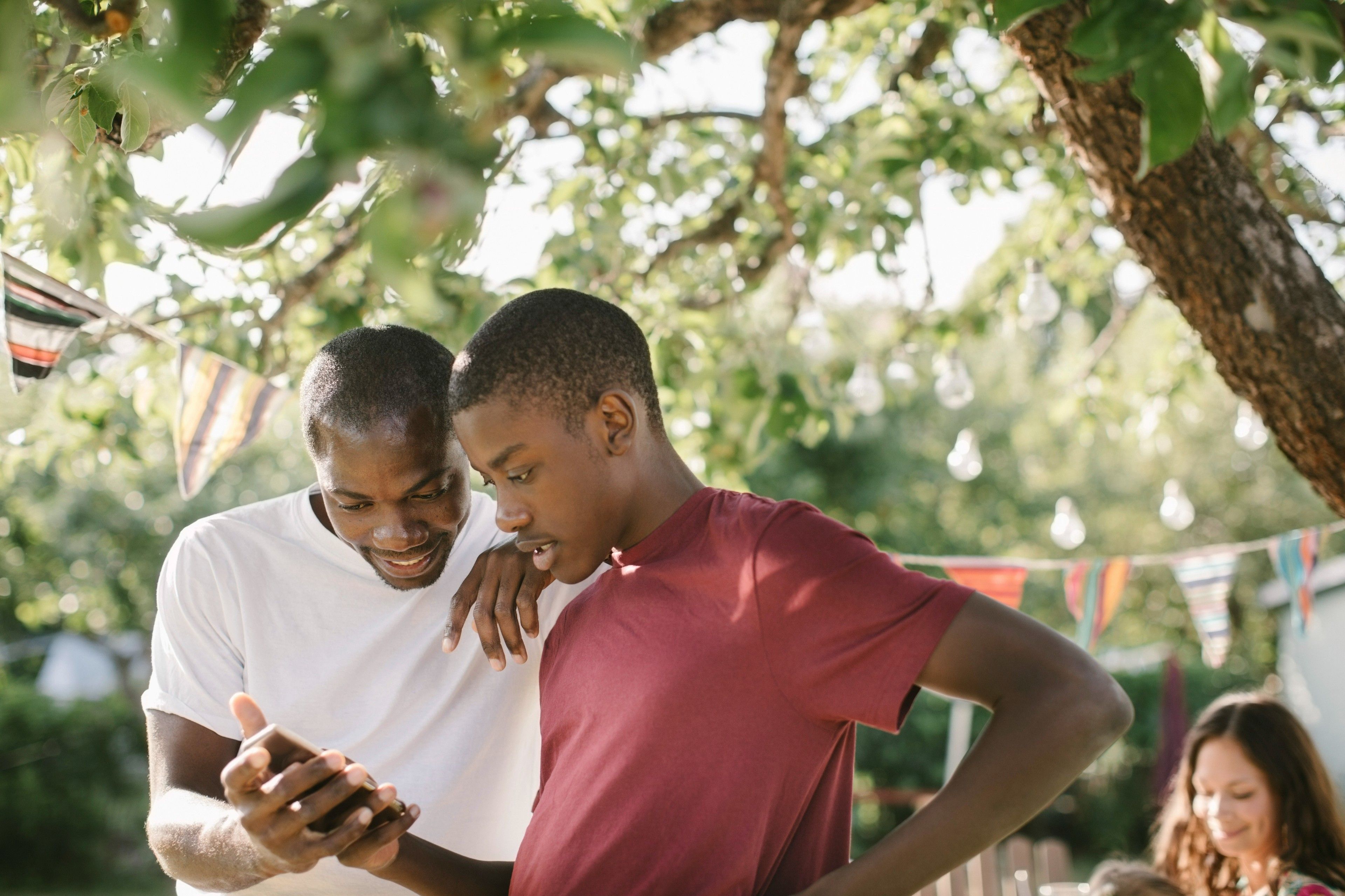 Two people watch a video on a mobile device at a family gathering