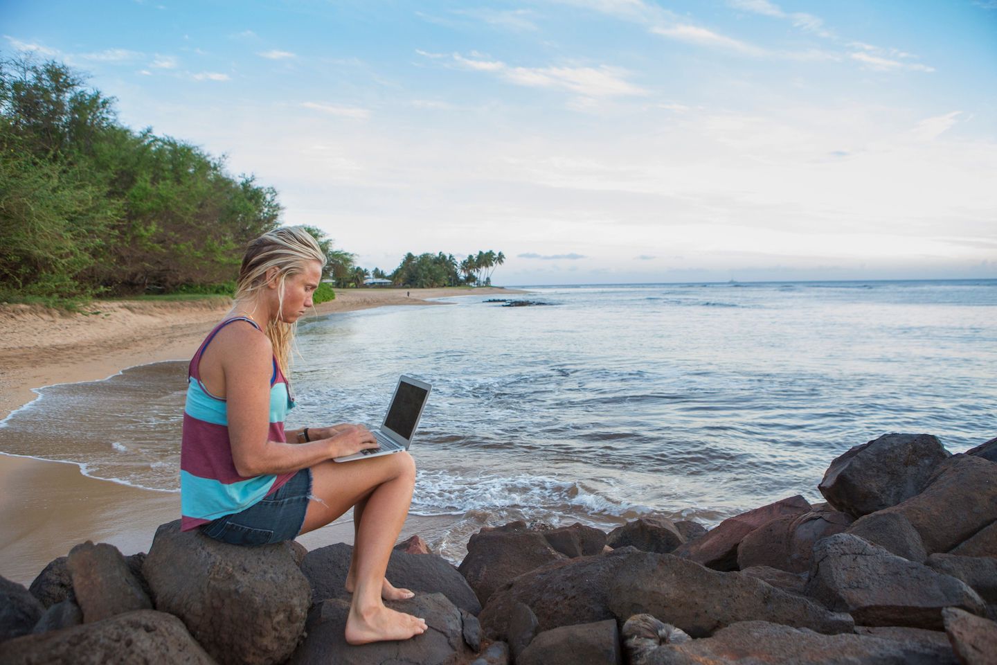 Seorang wanita bekerja dengan laptop di pantai