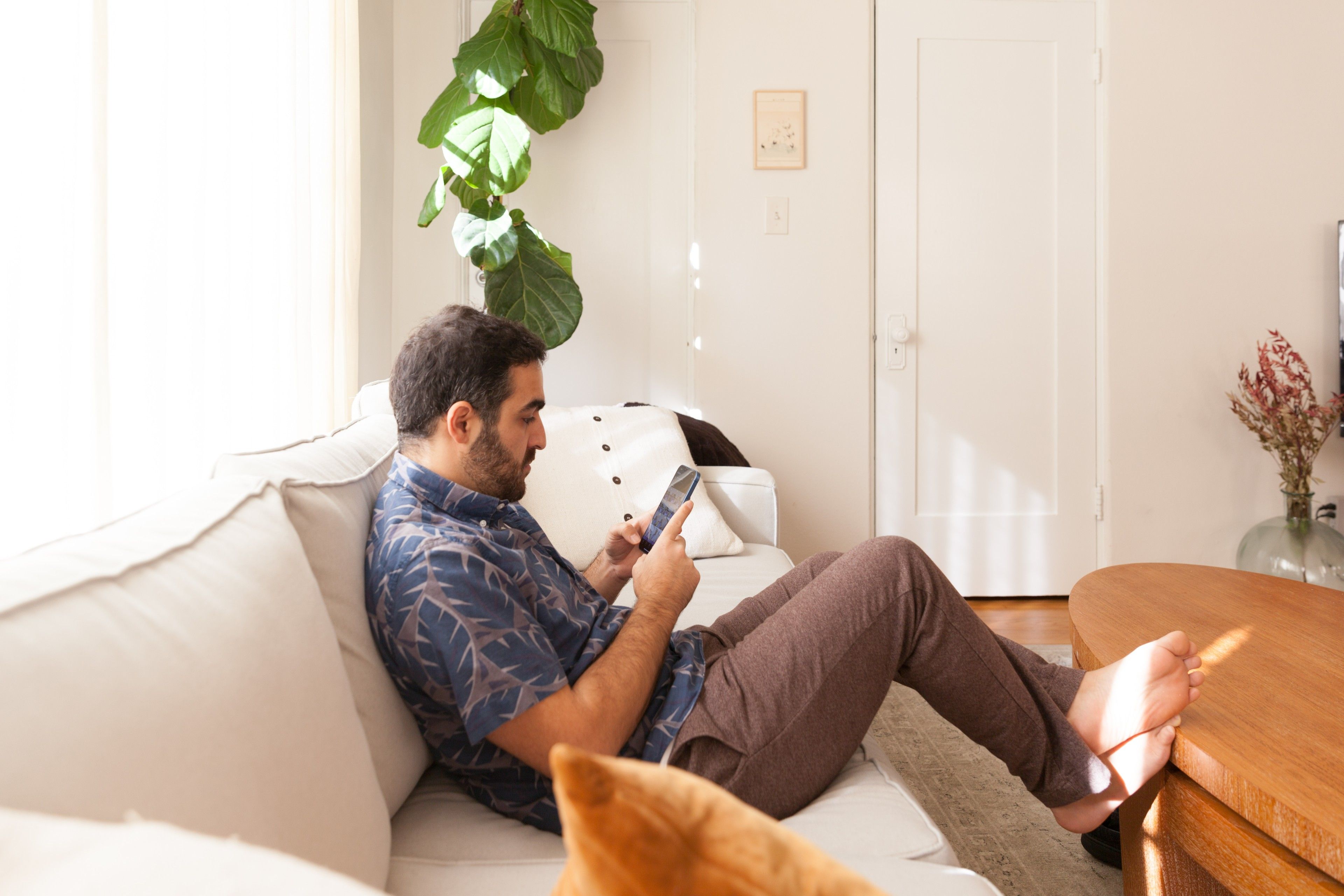 Ein Mitarbeiter im Home-Office verwendet sein Telefon, um mit Kollegen zu kommunizieren.