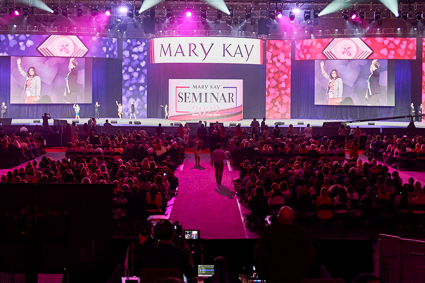 Conferencia Mary Kay con gente caminando por el escenario