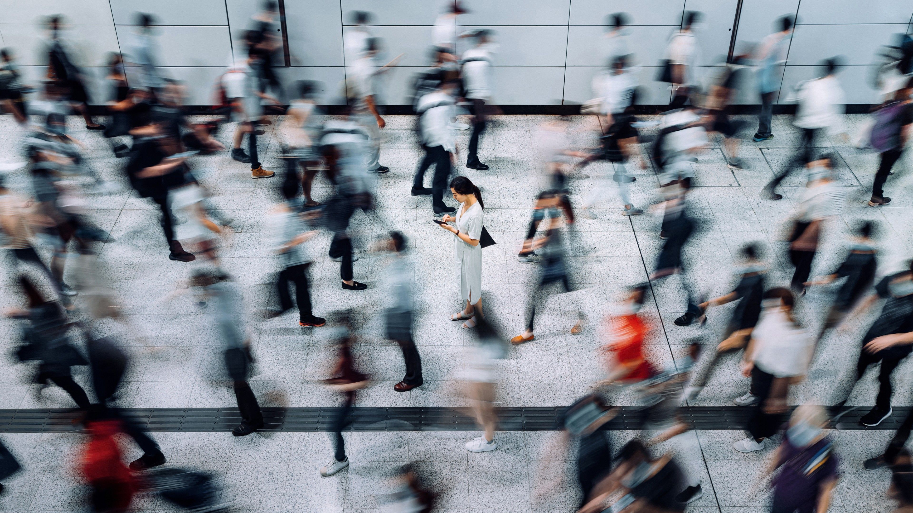 A person stops in a busy crowd to check an alert on their phone.