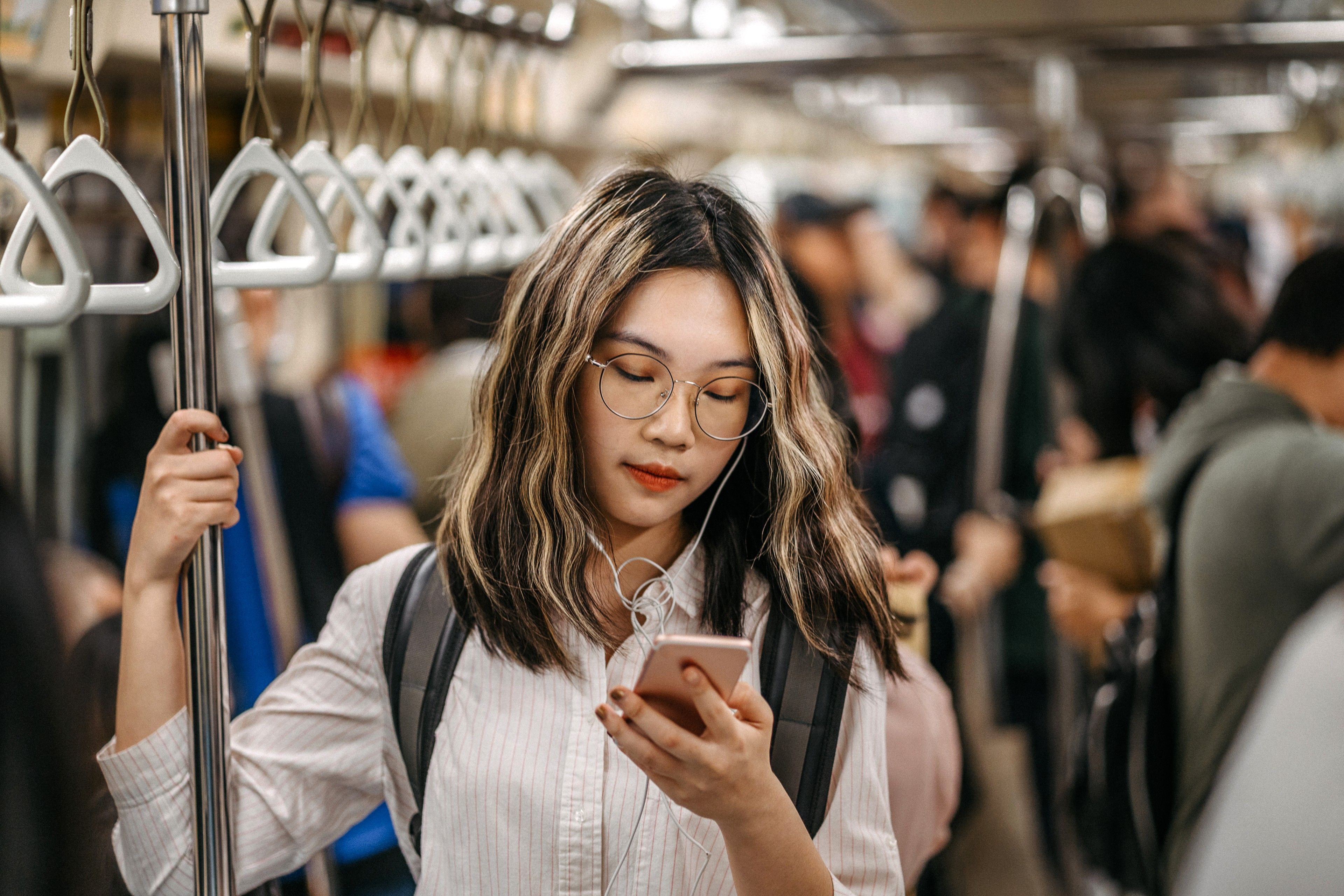 ​​Foto einer Person in einer U-Bahn, die mit ihrem Smartphone ein großes Video per SMS versendet