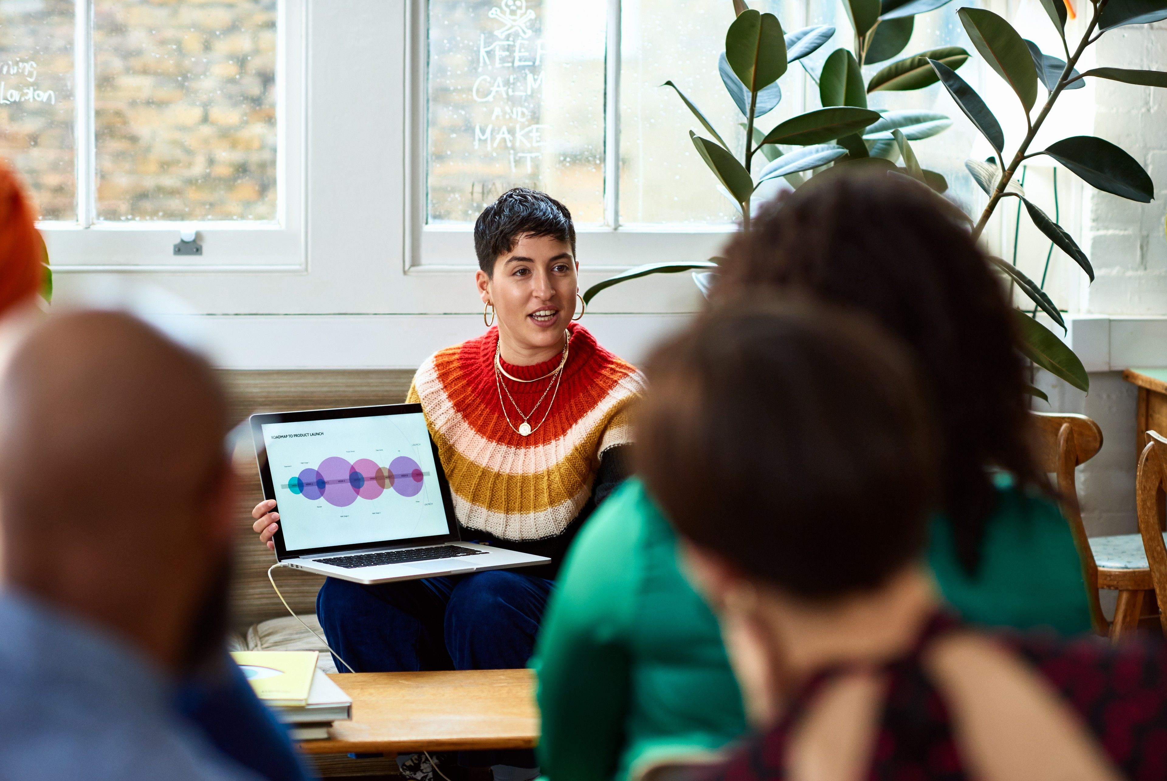 A professional presents a graphic on their laptop screen to their colleagues.