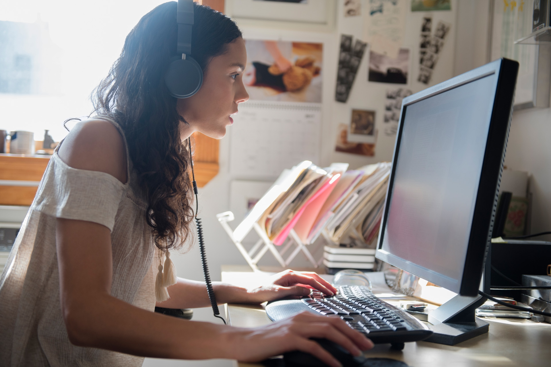 En person bär hörlurar och arbetar på en dator. 
